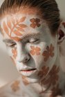 Ritratto di giovane con viso bianco e body art con fiori — Foto stock