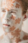 Ritratto di giovane con viso bianco e body art con fiori — Foto stock