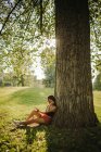 Женщина сидит под деревом и смотрит на свой мобильный телефон, Сербия — стоковое фото