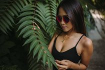 Asiatische junge Frau posiert mit grünen Baumblättern — Stockfoto