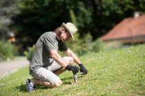 Portrait of a man kneeling in the garden setting up a water sprinkler, Germany — Stock Photo