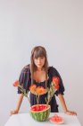 Mujer parada junto a un arreglo de flores de protea en una sandía - foto de stock