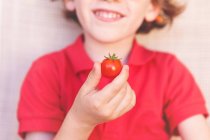 Улыбающийся мальчик держит помидор — стоковое фото