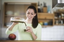 Frau steht in ihrer Küche und macht einen gesunden grünen Saft — Stockfoto