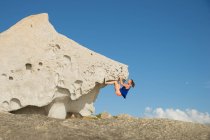 Woman rock climbing on natural boulder rock at the beach, Corsica, France — Stock Photo