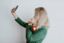 Woman holding Christmas bauble and taking selfie — Stock Photo