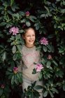 Портрет улыбающейся девушки, прячущейся в кустах рододендрона, Нидерланды — стоковое фото
