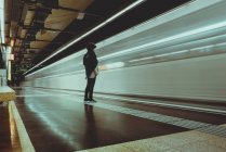 Женщина, стоящая в метро, когда поезд проезжает мимо, Испания — стоковое фото