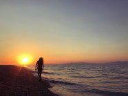 Silhouette d'un garçon marchant sur la plage au coucher du soleil, Grèce — Photo de stock