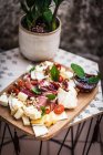 Charcuterie and cheese on a wooden chopping board — Stock Photo