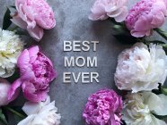 Peonías sobre un fondo gris alrededor de las palabras Best Mom Ever - foto de stock