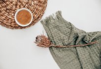 Tasse Kaffee neben einer getrockneten Protea-Blume und einer Decke — Stockfoto