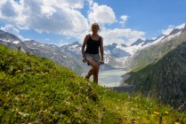 Femme souriante debout dans les montagnes en face du lac Oberaar, Grimsel Valley, Suisse — Photo de stock