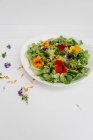 Assiette de salade verte aux fleurs comestibles — Photo de stock