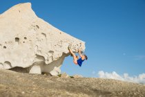 Frau klettert auf natürlichem Boulderfelsen am Strand, Korsika, Frankreich — Stockfoto