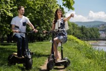 Couple on electric scooters taking a break by a river, Bosnia and Herzegovina — Foto stock