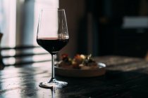 Verre avec vin rouge sur la table en bois dans le bar — Photo de stock