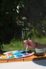 Mädchen sitzt im Garten und malt mit Aquarellfarbe — Stockfoto