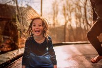 Smiling girl on a trampoline with her brother, USA — Stock Photo