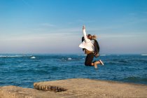 Frau springt am Strand in die Luft, Italien — Stockfoto