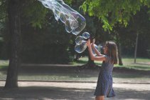 Menina brincando com bolhas gigantes em um parque, França — Fotografia de Stock