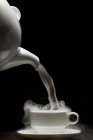 Steam being poured out of a teapot into a teacup — Stock Photo
