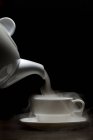 Dampf wird aus einer Teekanne in eine Teetasse gegossen — Stockfoto