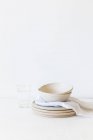 Керамические тарелки и миски рядом со стаканом воды — стоковое фото