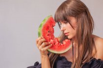 Mulher olhando para uma fatia de melancia — Fotografia de Stock