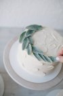 Femme décorant un gâteau à la crème au beurre avec des feuilles — Photo de stock
