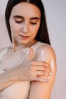 Femme frottant crème sur son bras — Photo de stock