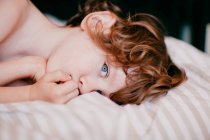 Retrato do menino ruivo deitado na cama — Fotografia de Stock