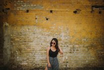 Stylish asian young woman standing in front of old brick wall — Stock Photo