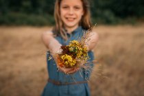 Ragazza sorridente in piedi in un campo che tiene un mazzo di fiori selvatici, Paesi Bassi — Foto stock