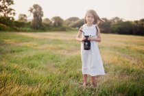 Fille debout dans un champ tenant une caméra vintage, Charleston, Caroline du Sud, États-Unis — Photo de stock
