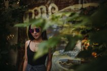 Asiatique dame portant lunettes de soleil vu à travers arbre feuillage — Photo de stock