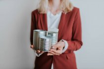 Cropped shot of woman holding three metal cans on white background — Stock Photo