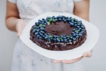 Жінка тримає шоколадний пиріг з чорниці. — стокове фото