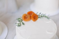 Primer plano de un pastel con glaseado de crema de mantequilla y decoración de melocotón - foto de stock