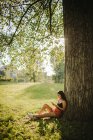 Frau sitzt unter einem Baum und blickt auf ihr Handy, Serbien — Stockfoto