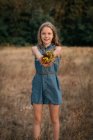 Lächelndes Mädchen auf einem Feld mit einem Strauß Wildblumen, Niederlande — Stockfoto