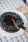 Woman serving a slice of blueberry chocolate brownie cake — Stock Photo