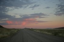 Estrada de cascalho pelo deserto ao pôr-do-sol, Namíbia — Fotografia de Stock