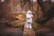 Niño cruzando un puente vestido como un yeti blanco para Halloween, Estados Unidos - foto de stock