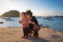Женщина, обнимающая свою дочь на пляже, Армакао-дус-Бузиос, Рио-де-Жанейро, Бразилия, — стоковое фото