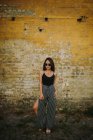 Elegante asiático joven mujer de pie en frente de viejo ladrillo pared - foto de stock