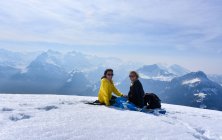 Две улыбающиеся женщины, сидящие на горе Фрональпсток, Швейцария — стоковое фото