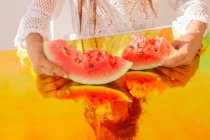 Woman holding slices of watermelon on holographic foil — Stock Photo