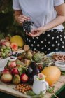 Cropped shot of woman by table with fresh fruit and vegetables — Stock Photo
