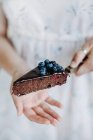 Woman holding a slice of blueberry chocolate brownie cake — Stock Photo